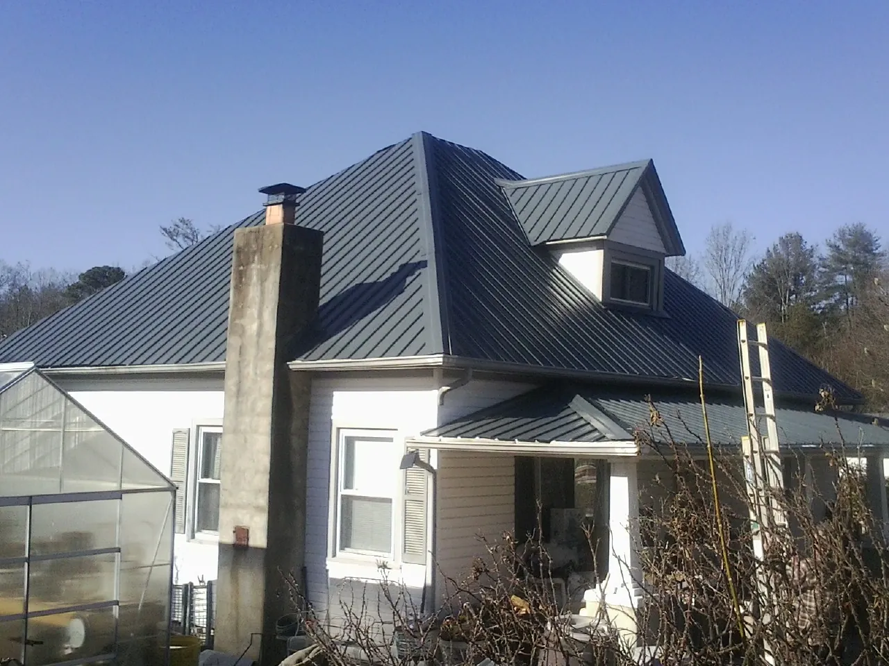 Dark blue standing seam metal roof on a white farmhouse with dormer — Slate & Tile Roof Repair by Roofing Brothers in Frankford