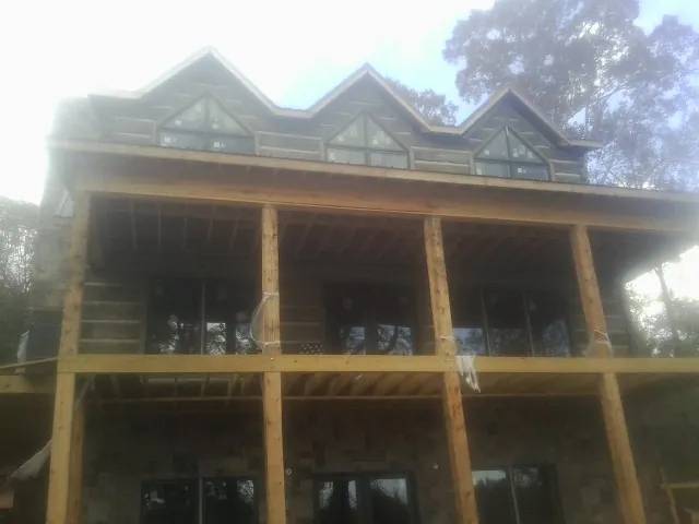 Dormers and porch framing on a large log home under construction — Roof Coating work by our crew in Frankford