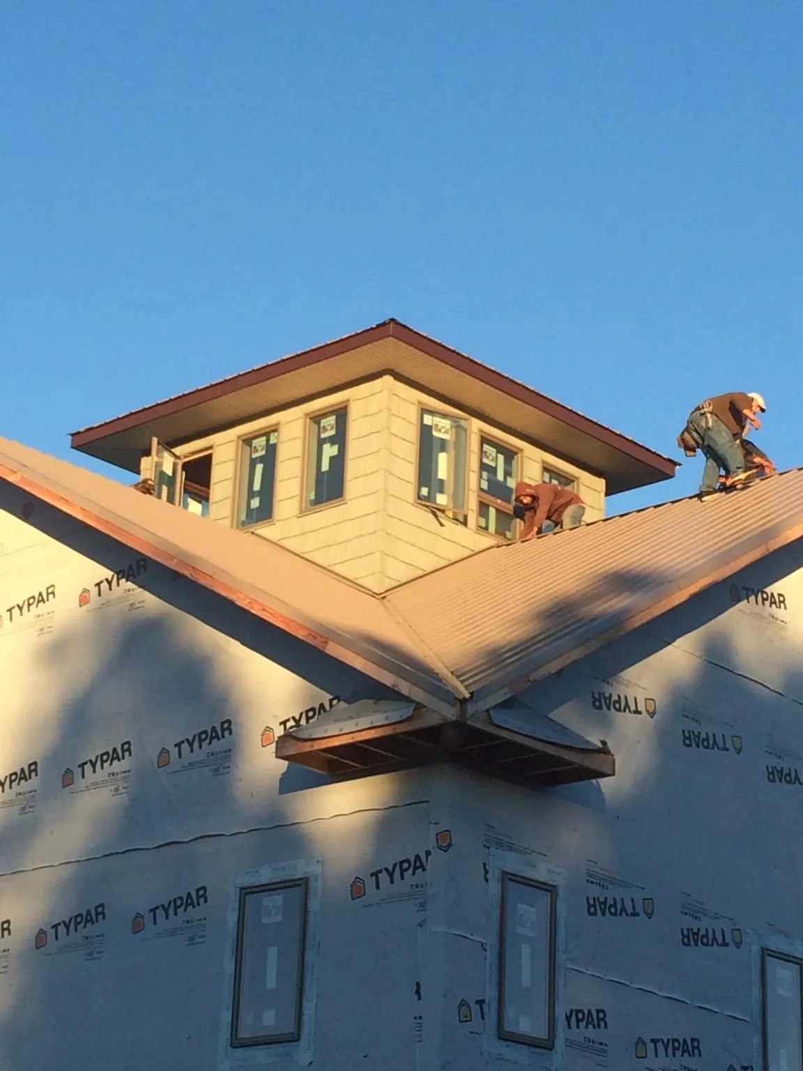 Roofers working around a rooftop cupola on a new metal roof at sunset — Roof Waterproofing in Frankford by Roofing Brothers